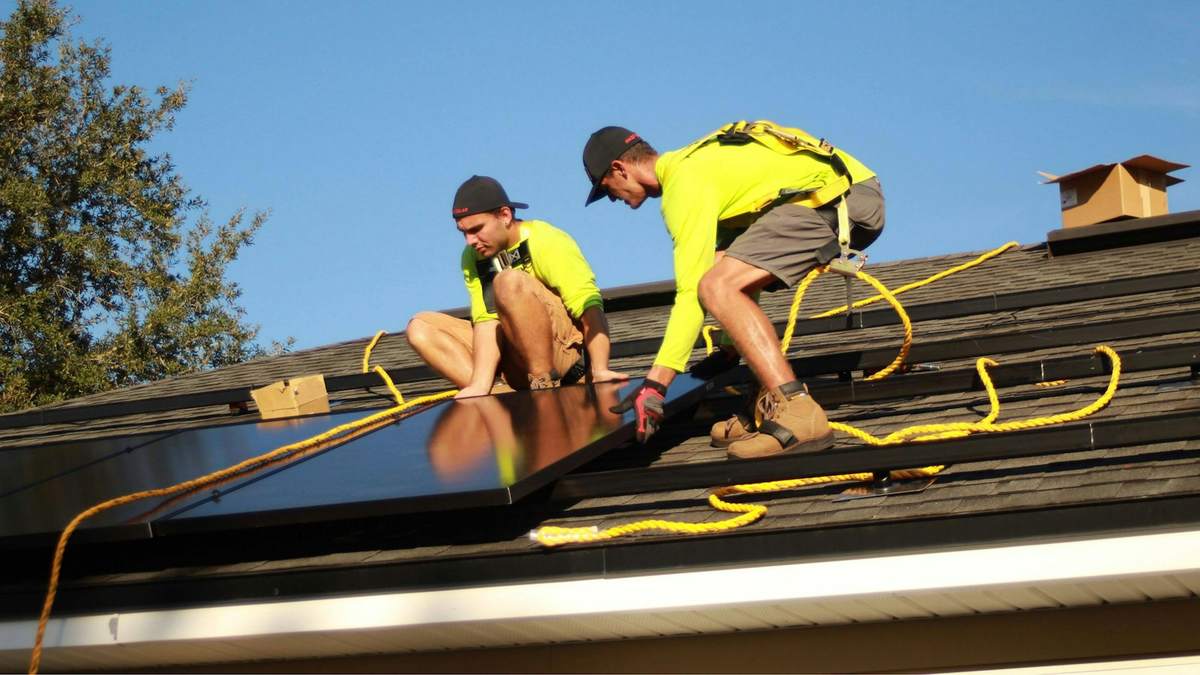 Installation crew fitting solar panels on a roof